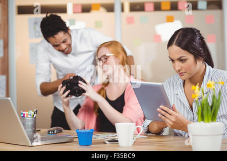 Businesswoman using digital tablet while colleagues looking at camera Stock Photo
