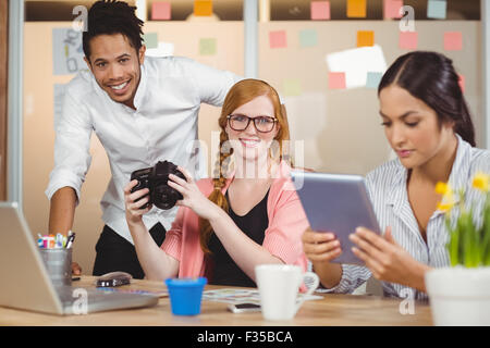 Colleagues holding camera with businesswoman using digital tablet Stock Photo