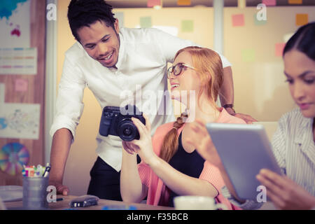 Colleagues holding camera with businesswoman using digital tablet in foreground Stock Photo