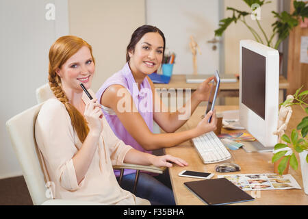 Businesswomen using tablet PC at desk Stock Photo