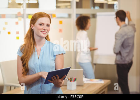 Smiling businesswoman using digital tablet with colleagues Stock Photo