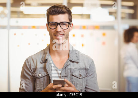 Businessman texting on phone with colleague working in office Stock Photo