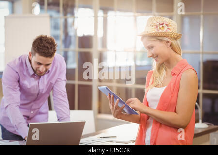 Business woman using digital tablet with male colleague working on laptop Stock Photo