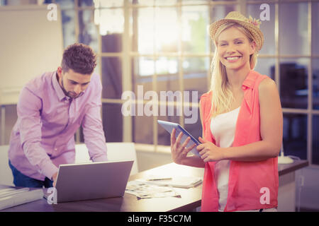Businesswoman with digital tablet by male colleague working on laptop Stock Photo