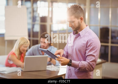 Businessman using digital tablet with colleagues on laptop Stock Photo