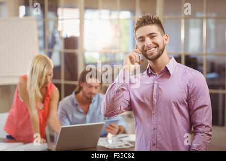 Businessman talking on phone in office with colleagues working Stock Photo
