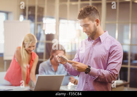 Businessman using on phone in office with colleagues working Stock Photo