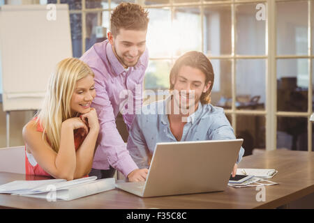 Smiling businessman using laptop while colleagues Stock Photo