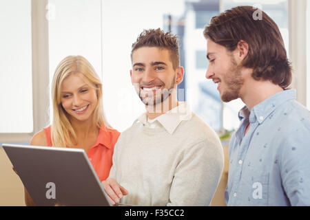 Businessman using laptop as colleagues looking at it Stock Photo