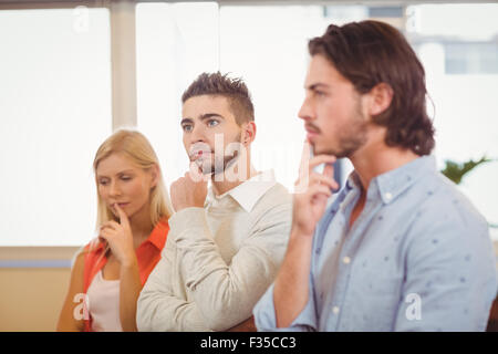 Thoughtful business people with hand on chin Stock Photo