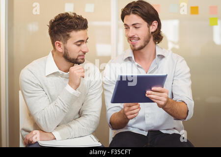 Businessman talking with male colleague using digital tablet Stock Photo