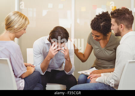 Business people consoling businessman suffering from headache Stock Photo