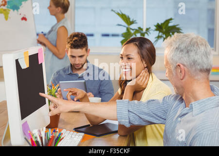 Businessman pointing on computer as female colleague looking at it Stock Photo