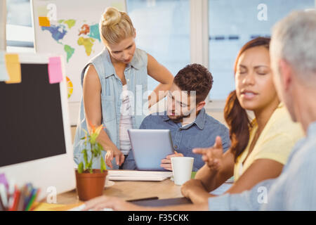 Businesswoman discussing with male colleagues using digital tablet Stock Photo