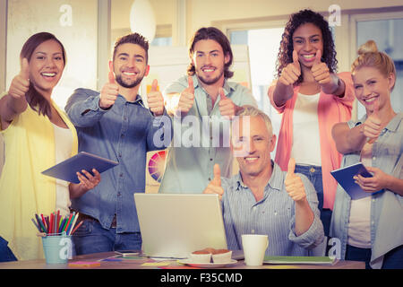 Business people with technologies showing thumbs up Stock Photo