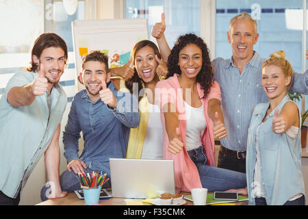 Happy business people with technologies showing thumbs up Stock Photo