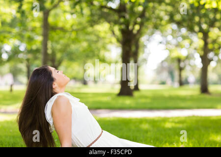 Side view of brown hair woman sitting on grass Stock Photo