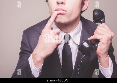 Young businessman is on the phone and is thinking about what to say Stock Photo