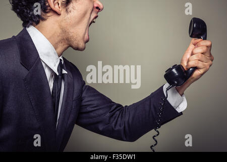 An angry young businessman is on the phone and screaming Stock Photo