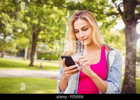 Smiling woman using smartphone in park Stock Photo