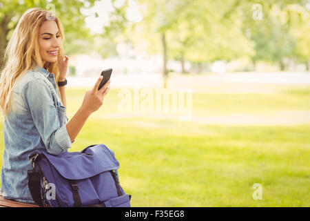 Smiling woman using smartphone at park Stock Photo