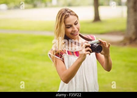 Smiling woman looking at digital camera while standing on grass Stock Photo
