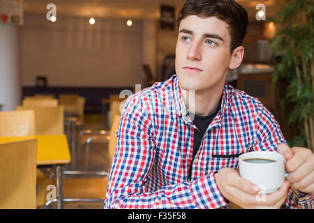 Thoughtful young man holding coffee cup Stock Photo