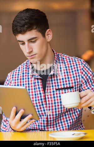 Young man using digital tablet while holding coffee cup Stock Photo
