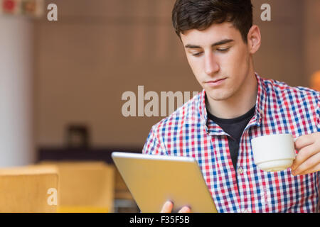 Young man using digital tablet while holding cup Stock Photo