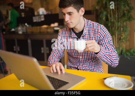 Young man with coffee using laptop Stock Photo