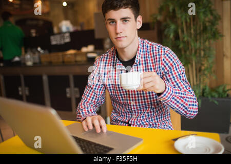 Portrait of young man with coffee using laptop Stock Photo