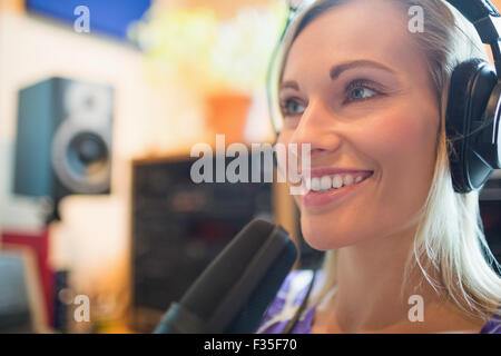 Young radio host wearing headphones using microphone studio Stock Photo