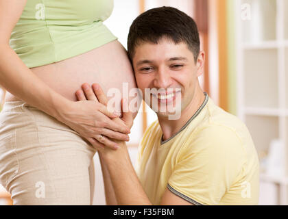 Portrait of a man listening the belly of his wife Stock Photo