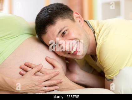 Happy man listening to belly of  his pregnant wife Stock Photo