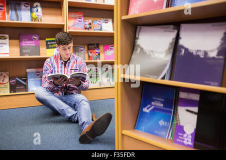 Young man reading book while sitting on floor Stock Photo
