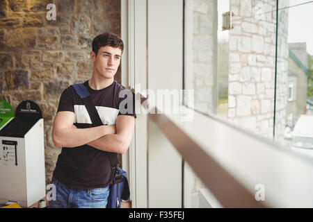 Thoughtful male student leaning on window Stock Photo