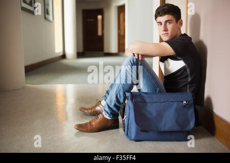 Portrait of male student sitting by wall Stock Photo