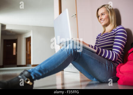 Female student sitting on flooring using laptop Stock Photo