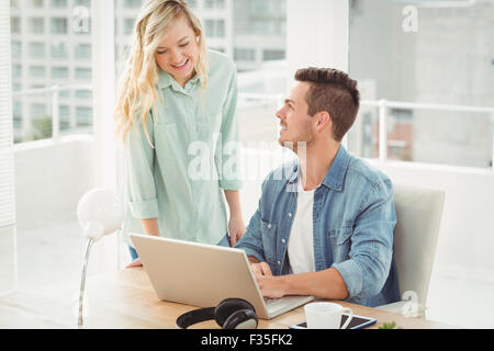 Smiling young coworkers working on laptop Stock Photo