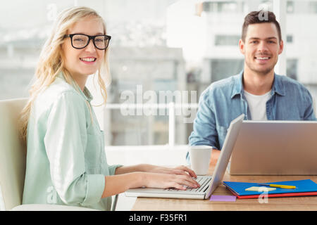 Portrait of happy woman wearing eyeglasses working on laptop with man Stock Photo
