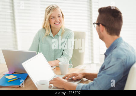 Smiling woman looking at man while sitting on chair Stock Photo