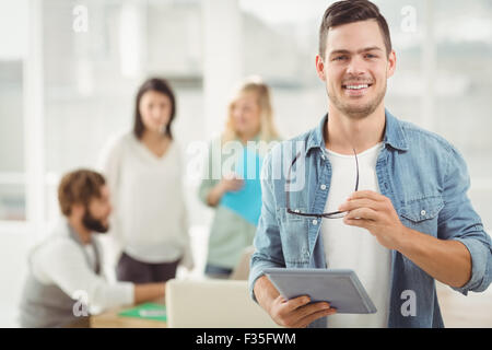 Portrait of happy man holding digital tablet and eyeglasses Stock Photo