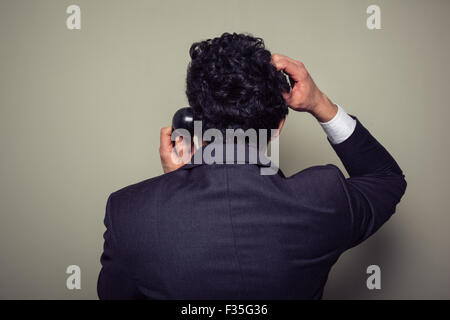 Rear view of a confused businessman on the phone scratching his head Stock Photo