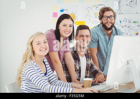 Portrait of smiling business professionals working at computer desk Stock Photo