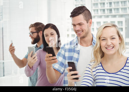 Happy business people using smartphones while standing in row Stock Photo