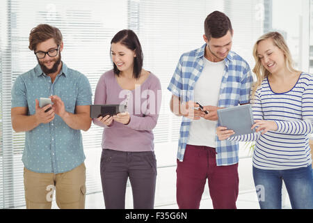 Smiling business people using electronic gadgets Stock Photo