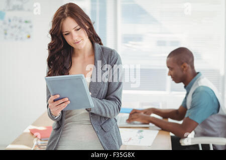 Woman using digital tablet with man working at desk Stock Photo