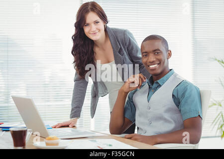Portrait of smiling business professionals working on laptop Stock Photo