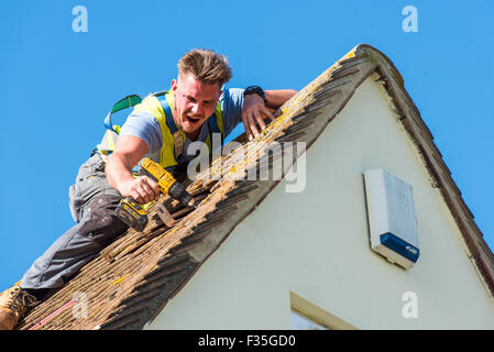 Roofer fitting bracket to roof joist to support a domestic solar panel system Stock Photo