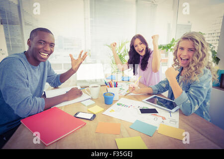 Portrait of smiling business people gesturing while sitting at desk Stock Photo